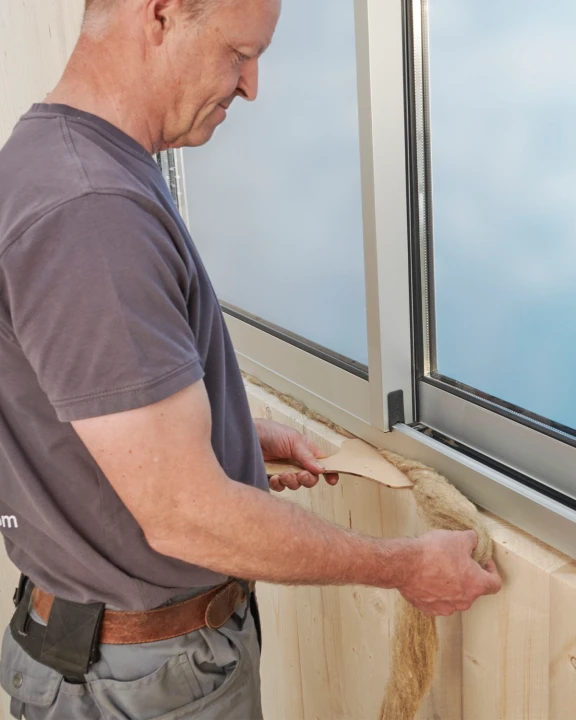 Montaż warkocza z wełny owczej ISOLENA w ramie okiennej